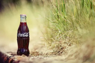 Макро фото бутылки Кока Колы в траве | Обои для телефона