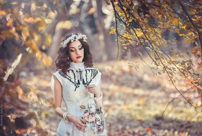 Фото Девушка с цветами на голове и с клеткой в руках и с бабочкой стоит  около осеннего дерева, фотограф Юлия Тульчинская