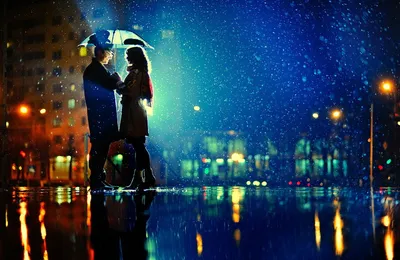 Обои на рабочий стол Мужчина и женщина, держащие в руках, сомкнутых вместе,  зонтик, смотрящие влюбленными глазами друг на друга, стоящие под падающим  мокрым снегом на асфальте в окружении световых бликов ночного города,