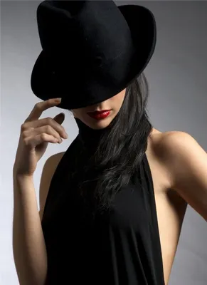 Фото Девушка в черной шляпе на черном фоне, волосы прикрывают лицо