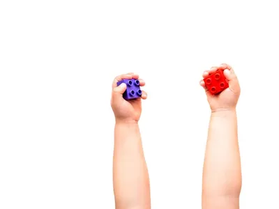 Ребенок держит фиолетовый и красный конструктор блоков в кулаках. | Премиум  Фото