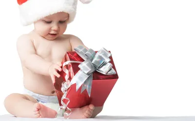 Обои на рабочий стол Малыш в шапке Санта Клауса открывает новогодний  подарок, обои для рабочего стола, скачать обои, обои бесплатно