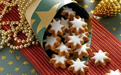 Обои на рабочий стол Печенье в глазури в виде звездочек в праздничной  упаковке, рядом лежат новогодние украшения, обои для рабочего стола,  скачать обои, обои бесплатно