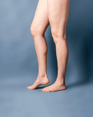 Женские длинные голые ноги на сером фоне ноги стоят на пальцах ног шпоры на  пятках | Премиум Фото