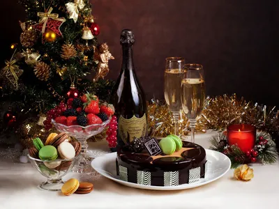 Обои на рабочий стол На столе у новогодней елки торт, конфеты, вазочка с  ягодами, вазочка с печеньем, бутылка шампанского, бокалы, свеча, новогодние  украшения, обои для рабочего стола, скачать обои, обои бесплатно