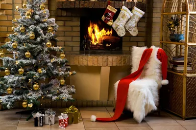 Новогодняя ёлка и носки для подарков, висящие у горящего камина - обои на  телефон