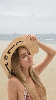 Фото A woman wearing a hat on the beach