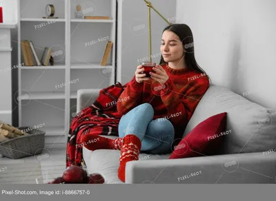 Фото Молодая женщина в красном свитере сидит дома на стуле